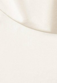 Cream-colored fabric with a smooth texture and subtle sheen, featuring a slight drape and curved seam detail in the design.