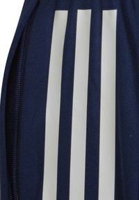 Navyblaue Sporttasche mit drei vertikalen weißen Streifen, aus strukturiertem Stoff gefertigt, mit einem Reißverschlussfach für die Aufbewahrung.