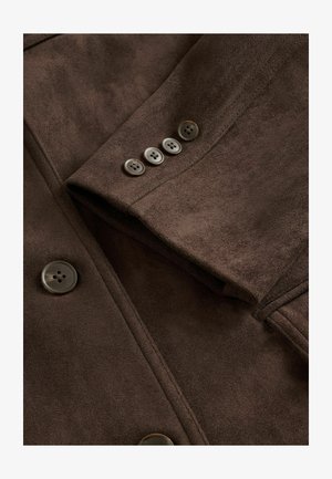 Veste en suedine marron avec un col à revers, fermeture à cinq boutons à l'avant et quatre boutons décoratifs sur la manche. Texture lisse.