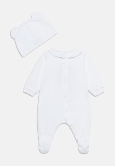 Λευκό μακρυμάνικο βρεφικό φορμάκι με κουμπιά στην πλάτη και συνοδευτικό καπέλο με μικρά στρογγυλά αυτιά, τοποθετημένα επίπεδα σε λευκό φόντο.