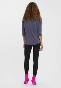 Long-sleeve gray top paired with black skinny jeans and pink heeled boots, showcasing a sleek silhouette and subtle texture.