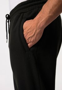 Zwarte sweatpants met een relaxte pasvorm, voorzien van een elastische tailleband, zijzakken en een subtiele logo detail nabij de zak.