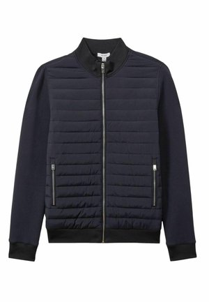 Chaqueta estilo bombardero de la marina con frente acolchado, mangas suaves, cuello y puños de canalé, que cuenta con dos bolsillos laterales con cremallera y cierre frontal con cremallera.