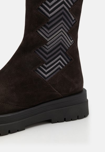 Pruunist seadmes valmistatud ankle boot, mille küljel on hallide toonidega zigzag-kootud muster ning must kummist tald, millel on tekstureeritud haardumine.