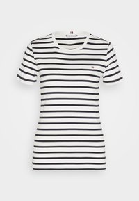 T-shirt blanc à manches courtes avec des rayures noires horizontales, présentant un col rond et un petit logo sur la poitrine gauche.