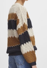 Stickad tröja med ett zickzackmönster i beige, brunt och marinblått; lös passform med ribbade ärmslut och nederkant; texturerad garn.