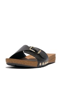 Zwarte leren sandaal met een brede strap, gouden gesp, kurken voetbed en kleine ronde metalen accenten op de buitenrand.