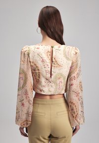 Gekürzte Bluse aus leichtem Stoff mit floralen Mustern in Rosa und Grün. Sie hat Puffärmel und einen Schlüsselloch-Rücken mit einem Knopfverschluss.