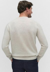 Ljust beige tröja i mjukt tyg, med rund halsringning samt ribbade ärmslut och nederkant. Designen är enkel och utan utsmyckningar.