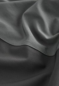 Gray fabric with a smooth, satiny texture, featuring subtle draping and a curved seam for added detail.