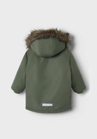 Parka verde con cappuccio foderato in pelliccia, maniche lunghe e striscia riflettente bianca sul retro. Costruzione in tessuto liscio e resistente.