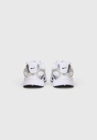 Sneakers značky Nike s převážně bílým svrškem, stříbrnými akcenty, texturovanou síťovinou a černou podešví. Navrženy pro atletické použití.