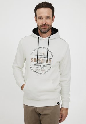 Hvid hoodie med en sort kantet hætte, har en frontlomme og trykt tekst i brun og sort. Beskårne manchetter og talje. Materialet er en blanding af bomuld.