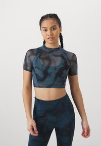 Top court à manches courtes en bleu canard avec des motifs abstraits noirs. Il présente un col montant et un design ajusté.
