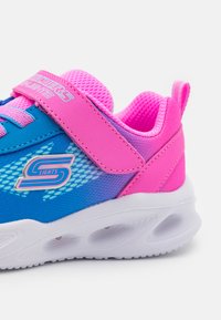 Μπλέ και ροζ αθλητικά παπούτσια με δίχτυ στην επάνω πλευρά, ρυθμιζόμενο λουράκι και λευκή σόλα με φωτεινές λεπτομέρειες. Υφασμάτινη σχεδίαση με χρωματική κλίμακα.