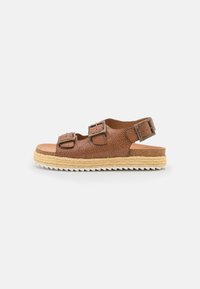 Brown textured leather sandal with two adjustable buckles, espadrille-style woven sole, and a white serrated rubber outsole.