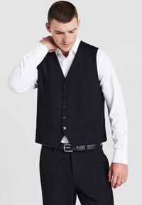 Schwarze Weste mit taillierter Passform, sechs Vorderknöpfen und zwei Taschen. Darüber getragen mit einem weißen Hemd, das eine glatte Textur und eine maßgeschneiderte Form aufweist.