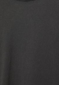 Tessuto di cotone nero con una superficie liscia, caratterizzato da un collo a giro e una leggera sfumatura, creando un aspetto morbido e discreto.