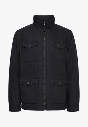 Melna jaka ar augstu apkakli, priekšējo rāvējslēdzēju un vairākām kabatām ar atloku. Gluda auduma un izturīga dizaina, piemērota ikdienas valkāšanai.