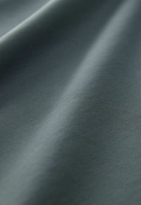 Tela suave de color gris oscuro con pliegues suaves y textura fina y tupida visible en primer plano.