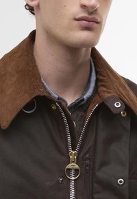 Barna pamutdzseki, kordbársony gallérral, ezüst cipzárral, sárga kiegészítőkkel és texturált belső béléssel.