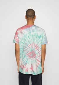 Koszulka z bawełny w technice tie-dye w pastelowych kolorach, z spiralami w odcieniach różu, zieleni i niebieskiego. Krótkie rękawy, okrągły dekolt, luźny krój.