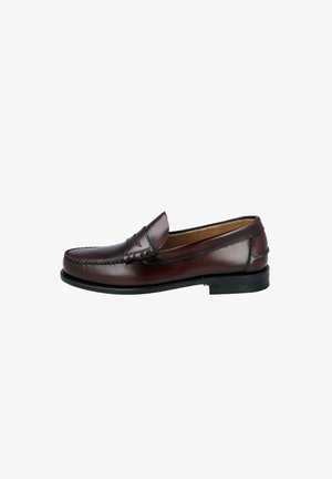 Mocasín clásico de cuero marrón oscuro con detalle de costuras y suela negra, mostrado en perfil izquierdo sobre fondo blanco.