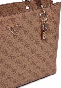 Sac fourre-tout en brown avec une texture et un motif en diamant, accessoires en métal doré, logo triangulaire et porte-clés.
