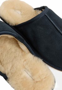 Svarta mockaskor med en mjuk krämfärgad shearlingfoder och en kontrasterande m�örk trim. Rundad form med öppen tådesign.