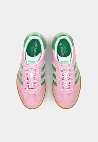 Zapatillas de ante rosa con rayas verdes y blancas, punta redonda, cordones planos y suela de goma. Presenta una plantilla con marca.