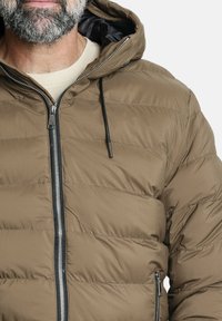 Chaqueta de plumas marrón con cremallera frontal, costuras horizontales y capucha ajustable. La tela es suave con un acabado mate.