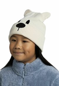 Gorro de punto blanco con dibujo de cara de oso negro; presenta orejas en la parte superior y tiene una textura suave. Se lleva con una chaqueta de forro polar azul.