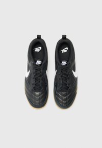 Schwarze Sportschuhe mit einem strukturierten Lederobermaterial, weißem Nike-Swoosh und Gummisohle. Verfügt über einen gepolsterten Schaft und ein Schnürdesign.