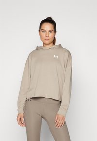 Sudadera recortada beige con capucha y cordón, y logo blanco. Combinada con leggings beige a juego, que presentan una textura suave y lisa.