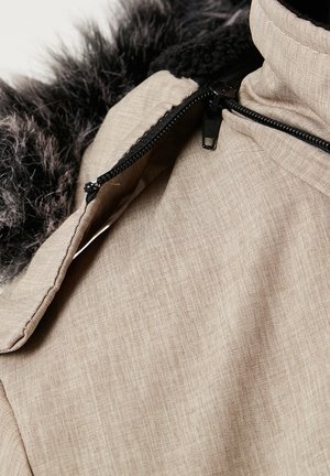 Giacca zip-up beige chiaro con tessuto testurizzato, dotata di colletto in pelliccia sintetica grigio scuro e dettagli della cerniera nera.