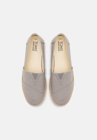 Gray canvas shoes with an elasticized V-shaped opening, jute sole, and smooth interior lining. Brand logo visible on the insole.