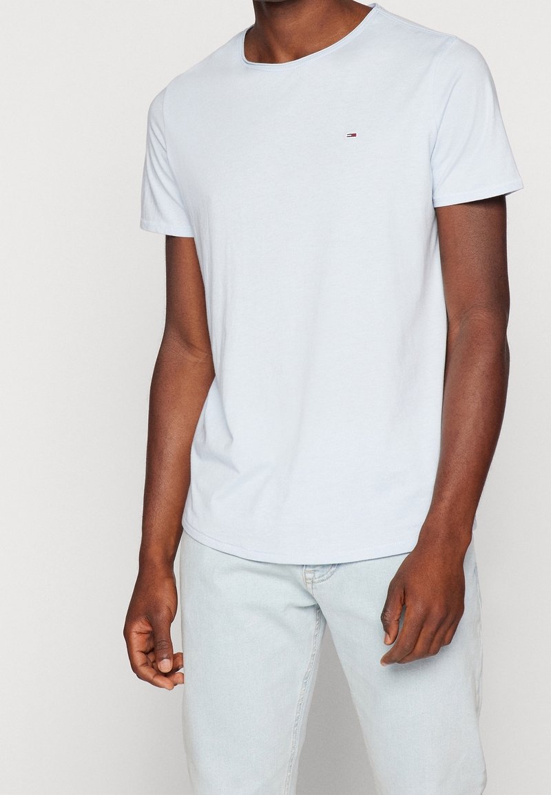 Světle modré bavlněné tričko s kulatým výstřihem, krátkými rukávy a malým logem na hrudi. Texturovaná tkanina, volný střih.