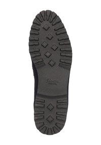 Zwarte rubberen zool met diep looppatroon, met hexagonale en diamantvormige figuren voor grip. Het merklogo is zichtbaar nabij het midden.