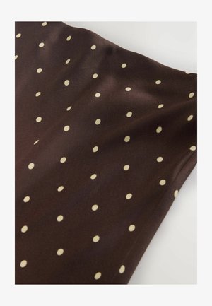 Brunt stof med en glat tekstur, der har jævnt fordelt cremefarvede polkaprikker, hvilket skaber et legende mønster over overfladen.