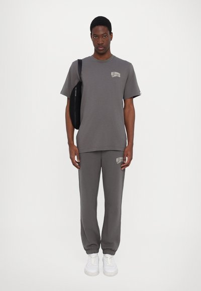 Grijze katoenen t-shirt met een geprinte logo op de borst, gecombineerd met bijpassende joggingbroek met logo-detail; beide ontworpen voor een losse pasvorm.