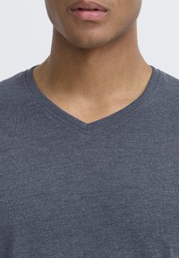 Grå v-hals t-shirt lavet af blødt, letvægtsstof. Har en glat overflade og en klassisk snit omkring halsudskæringen.