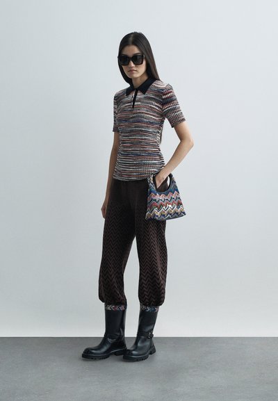 Knit polo shirt with colorful stripes, black collar; brown zigzag-patterned pants; black boots; small handbag with multicolored zigzag design.