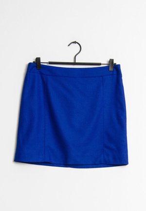 Blå uld mini-skjørt hængende på en sort bøjle mod en enkel hvid baggrund.