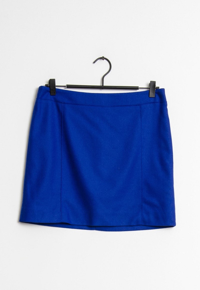 Jupe mini en laine bleue accrochée à un cintre noir sur un fond blanc uni.