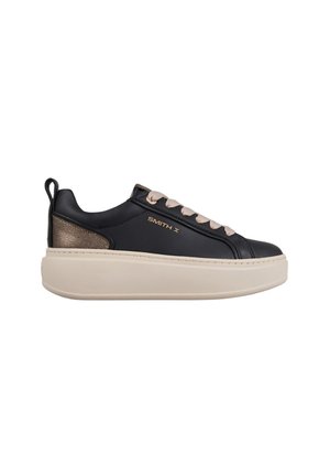 Sneakers in pelle nera con suola piatta beige, dotate di un accento metallico sul tallone e lacci color taupe chiaro. Logo del marchio sul lato.