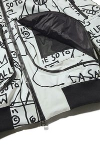 Fehér párnázott dzseki fekete absztrakt mintákkal, cipzárakkal, hálós zsebbel és bordázott mandzsettákkal. Texturált, könnyű anyagból.