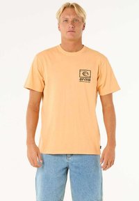 Oranje katoen T-shirt met korte mouwen, ronde hals, voorzak met een grafisch golflogo, gecombineerd met lichtblauwe denim shorts.
