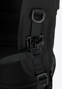 Mochila negra con material de nailon texturizado, correas ajustables, detalles de malla y herrajes de plástico para un cierre seguro.