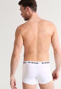 Boxer in cotone bianco con vita nera G-Star, design aderente, texture liscia e copertura minima. Vista dal retro.