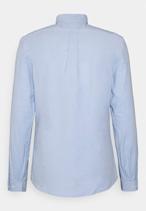 Chemise à manches longues bleu clair avec un pli au dos, en tissu doux, poignets à bouton et col classique. Texture lisse avec une coupe décontractée.